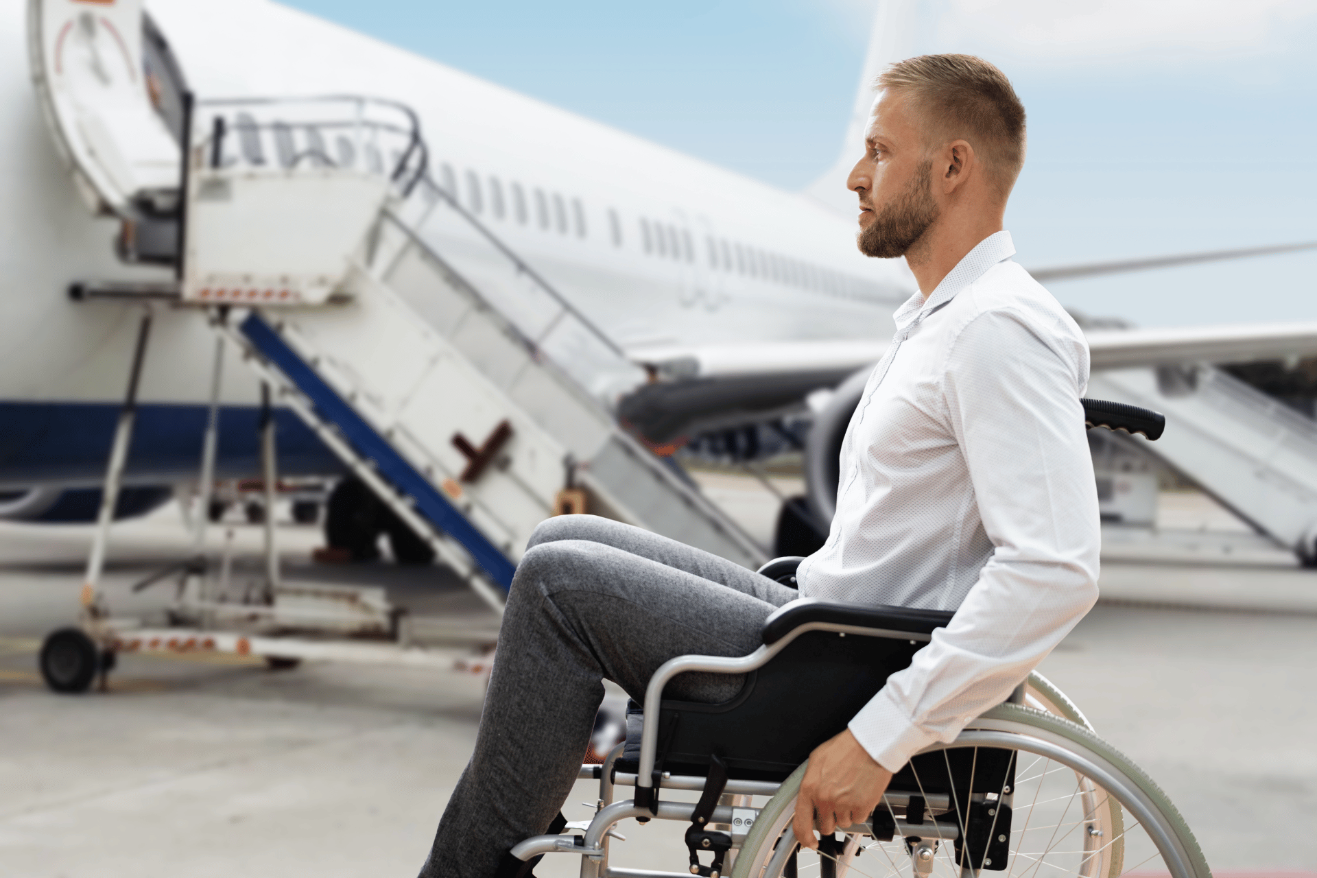 A man in a wheelchair outside an aeroplane on the tarmac