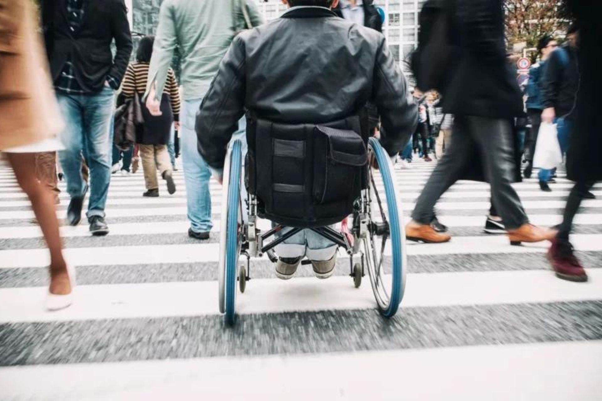 Person in wheelchair crossing a zebra crossing.