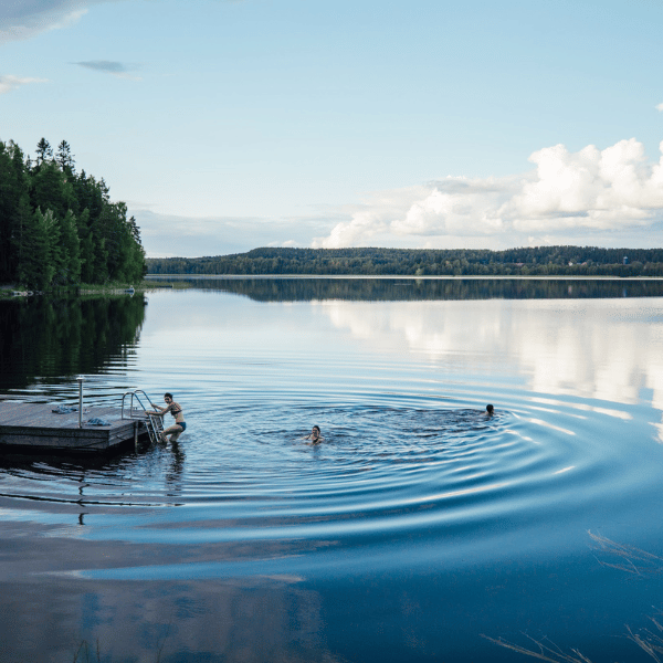 A quiet lake in Finland with people in the water ©Visit Finland