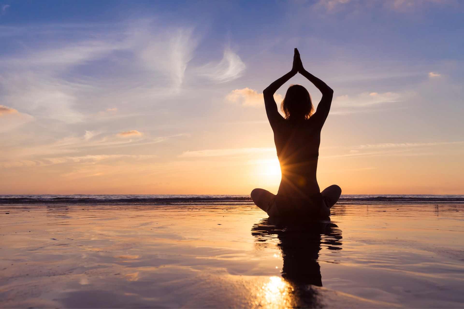 Young woman practicing yoga on a beach at Sunrise. ©Getty Images
