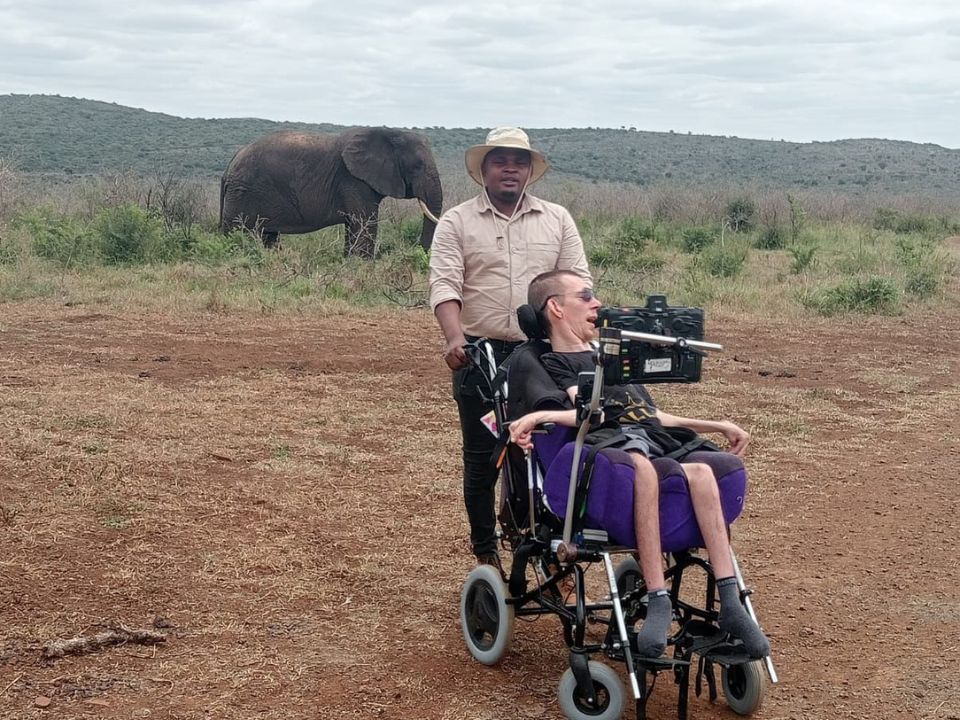 A man in a wheelchair sitting in front of an elephant